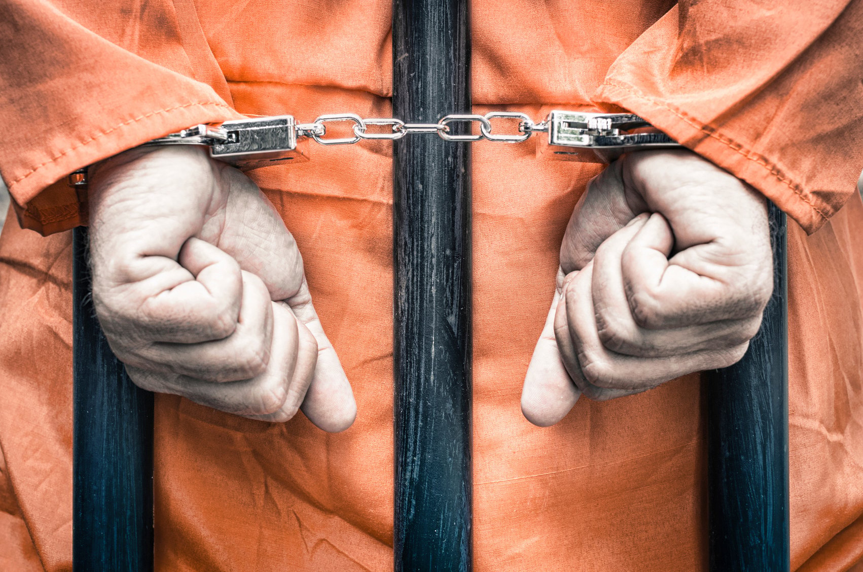 Handcuffed-hands-of-a-prisoner-behind-prison-bars-000047763880_Medium-2